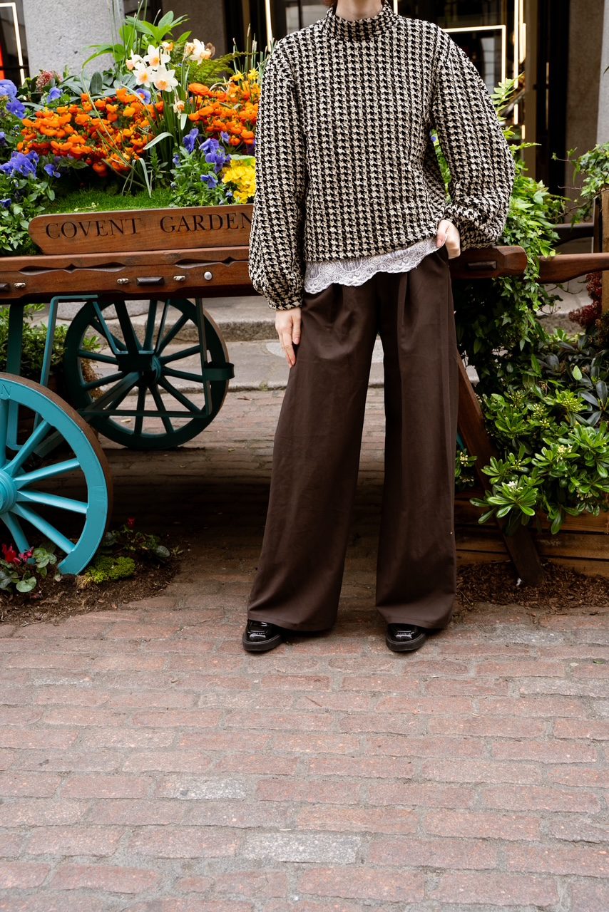 Houndstooth knit top and wide-leg brown trousers in front of a Covent Garden flower cart
